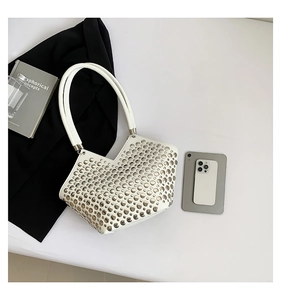 Détail d'un sac cabas en cuir blanc orné de clous argentés avec une bordure en forme de V