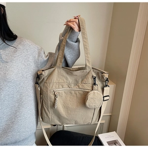 Detail of khaki nylon tote bag showing front zip pocket and detachable round coin purse