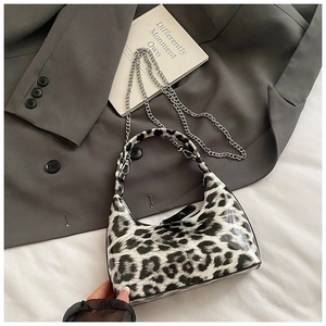 Detail of glossy leopard print handbag with metal chain strap and top handle