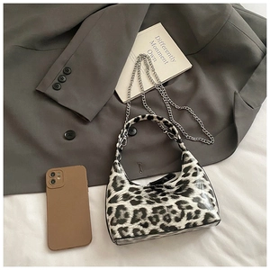 Detail of leopard print handbag with glossy finish and silver chain on suit jacket