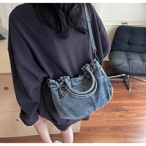 Dettaglio della borsa in denim lavato con cuciture doppie e rivetti in metallo