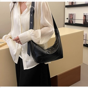 Side view of a black crescent shoulder bag with minimalist diagonal stitching details