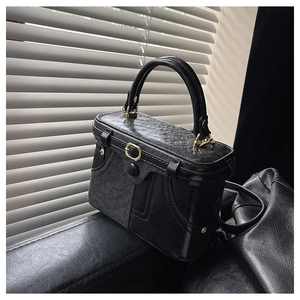 Detail of a vintage black box handbag with textured leather and gold hardware accents