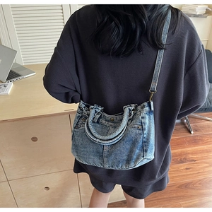 Dettaglio della borsa tote in denim retrò con tasche in vita ed elementi in metallo