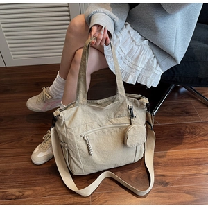 Detail of a beige nylon tote bag with a matching coin purse shown in a lifestyle setting