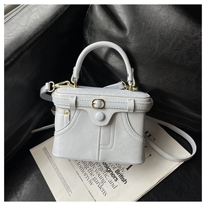 Detailed shot of retro denim-style leather box bag with gold buckle and adjustable strap