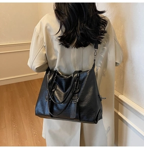 Detail view of a large black PU leather tote bag worn as a shoulder bag on a model