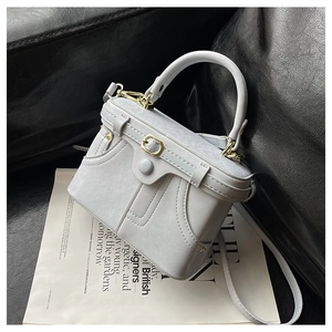 Detailed view of grey vintage box bag with gold hardware on a leather surface
