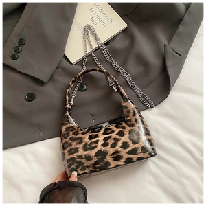 Detail of glossy leopard print handbag featuring shiny PVC coating and silver chain strap