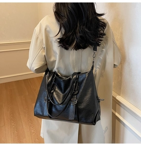 Close-up of black leather tote bag featuring litchi texture and adjustable shoulder strap