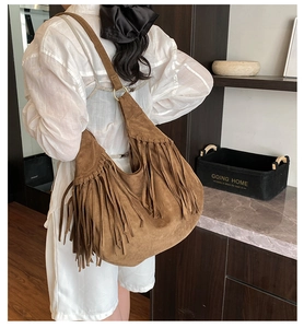 Close-up of brown suede hobo bag featuring vintage long tassels and metallic ring detail