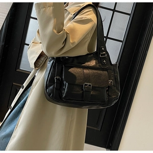 Close-up of black leather tote bag with vintage texture and metallic buckle details