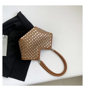 Détails des rivets métalliques argentés sur un sac bandoulière punk en cuir marron poli
