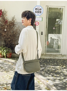Sac bandoulière en nylon vert armée porté par un modèle en extérieur pour la taille