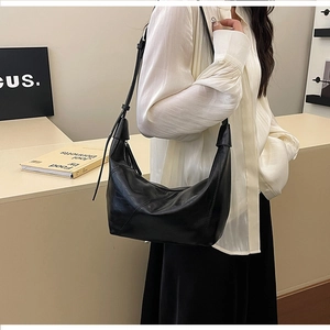 Minimalist black leather hobo bag with adjustable strap shown on model in studio