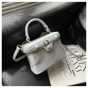 Detailed view of structured box bag with gold-tone buckle and round handle on black leather