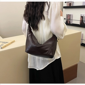 Deep brown large leather hobo bag with knotted strap detail shown on a model