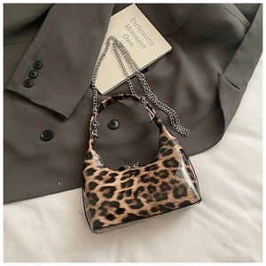 Detailed close-up of glossy leopard print hobo bag with a silver chain on grey blazer