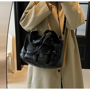 Detail of black vintage cracked leather handbag with silver buckles and adjustable strap