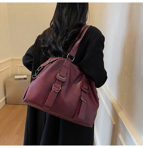 Burgundy faux leather tote bag with pebble texture and decorative buckle on a model