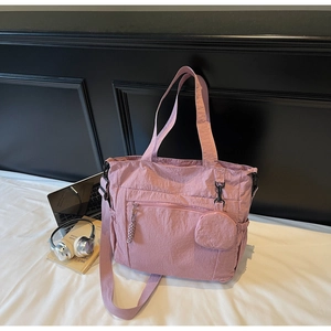 Detail of dusty pink nylon tote bag with texture, outer zipper, and small round pouch