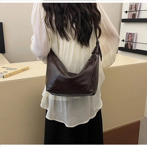 Chic dark brown hobo bag worn by a model in a minimalist and elegant interior setting