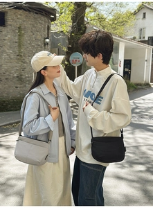 Détail de sacs bandoulière minimalistes en nylon noir et gris clair pour les couples