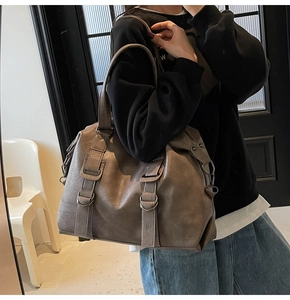 Detail view of large taupe tote bag with metallic ring buckles and leather texture