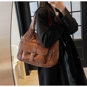 Close-up of a vintage brown large capacity tote bag with front pocket and buckle detail