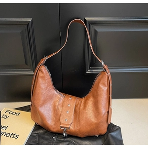 Detail of a brown hobo tote bag featuring star-shaped metal rivets and litchi grain texture