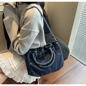 Dettaglio della borsa tote in denim blu scuro con tasche e rivetti metallici