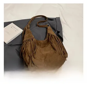Detail of dark brown suede hobo bag featuring bohemian fringe and gold metal ring buckle
