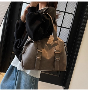 Detail of dark brown tote bag with vintage matte leather texture and silver buckles
