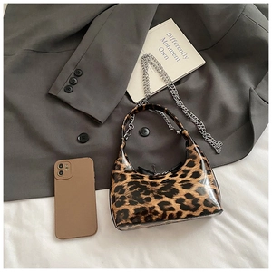Detailed macro view of glossy leopard print crescent bag with silver chain and smartphone