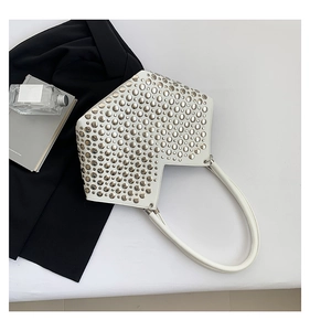 Vue macro d'un sac à bandoulière en cuir blanc avec rivets argentés et forme géométrique