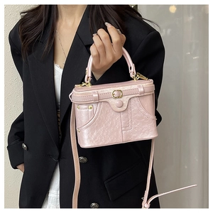 Detail of pink vintage box bag featuring denim pocket design and gold hardware
