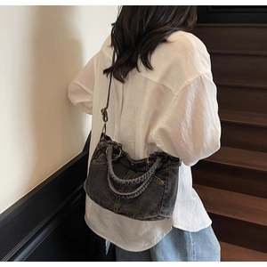 Borsa tote in denim lavato retrò con manici intrecciati e borchie sulla modella