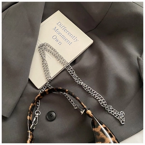 Close-up of glossy leopard print handbag with refined silver chain straps and sleek metal finish