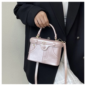 Detail of pink faux leather bag with jacket-style pocket and metallic buckle accents