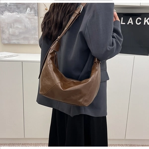 Detail view of the deep brown hobo bag showing its premium smooth texture and metallic buckle