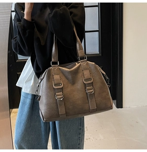 Detail of the vintage brown PU leather tote with metal buckle and vertical decorative strap