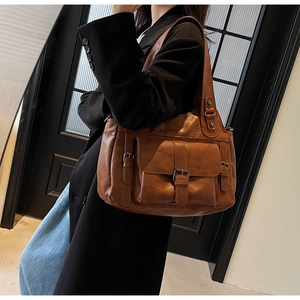 Detail view of brown vintage tote bag with crushed texture and flap buckle pocket
