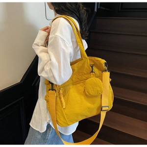 Bright yellow nylon tote bag with matching round zipper charm and wide shoulder strap