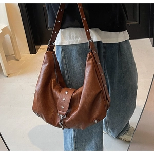 Detail of vintage dark brown faux leather hobo bag with star rivets and adjustable strap