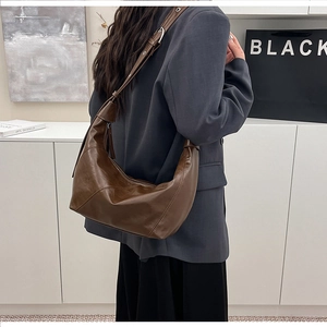 Detailed view of dark brown leather hobo bag with adjustable strap and stitched seams