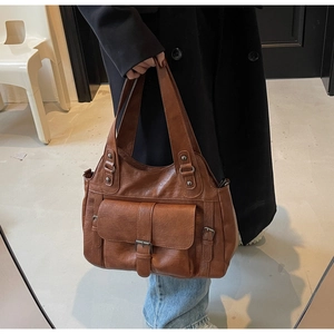 Detailed side view of a brown vintage leather tote bag with metal buckle pocket