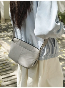 Détail montrant la bandoulière réglable et le compartiment zippé du sac dumpling gris