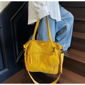 Detail of yellow nylon tote bag showing the matching round coin purse and wide strap