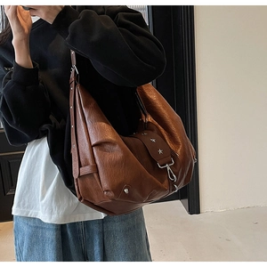 Detail of soft brown leather tote bag featuring a vintage star-shaped metal ornament