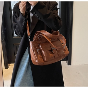 Detail view of brown vintage leather handbag with reinforced straps and metal buckles